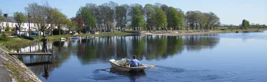 view of burgess park in athlone with river shannon and man in rowboat in the foreground
